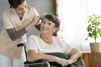 caregiver combing hair of old woman