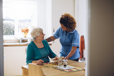 caregiver giving dinner to old woman